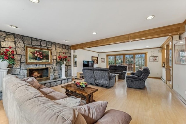 living area featuring baseboards, ornamental molding, a stone fireplace, light wood-style floors, and a baseboard heating unit