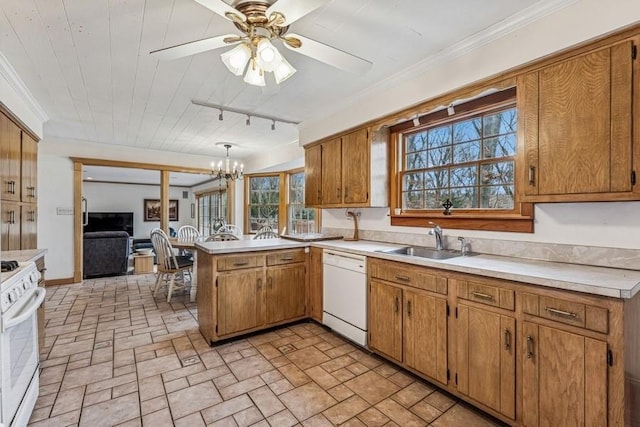 kitchen with a peninsula, white appliances, light countertops, and a sink