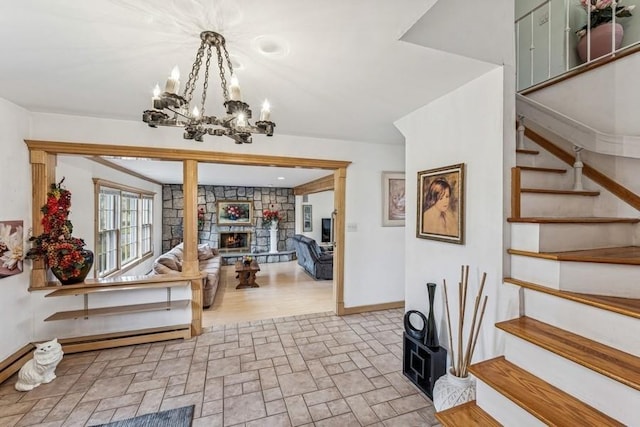 interior space with a fireplace, a baseboard heating unit, stone finish flooring, a chandelier, and baseboards