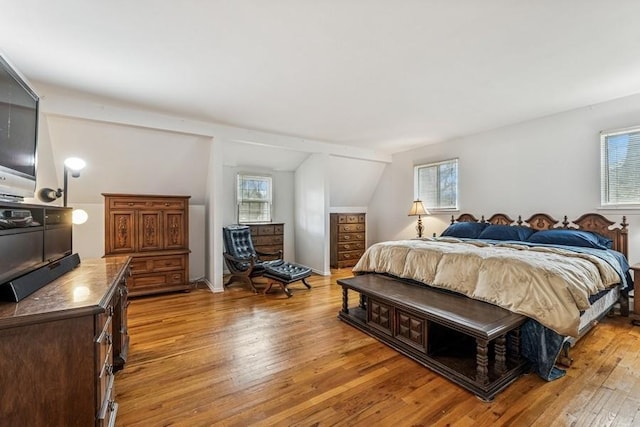 bedroom featuring multiple windows, vaulted ceiling, and light wood-style flooring