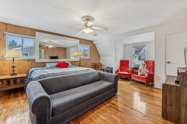 bedroom with wood-type flooring, wood walls, and ceiling fan