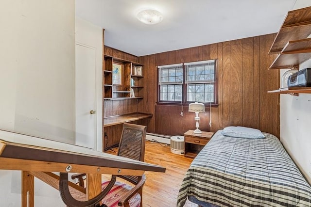 bedroom with light wood-style flooring, wooden walls, and a baseboard heating unit