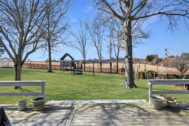 view of home's community with a playground, a yard, a deck, and fence