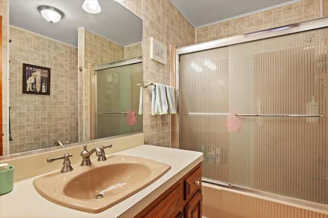 full bathroom featuring tile walls, vanity, and bath / shower combo with glass door