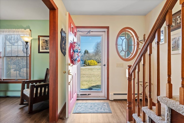 entrance foyer with stairway, baseboard heating, and wood finished floors