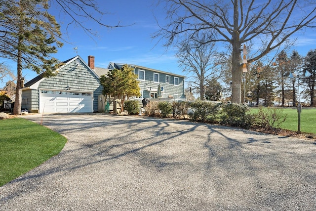 view of front of home featuring a garage, driveway, a front lawn, and a chimney