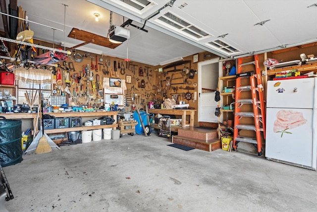 garage with a workshop area, freestanding refrigerator, and a garage door opener