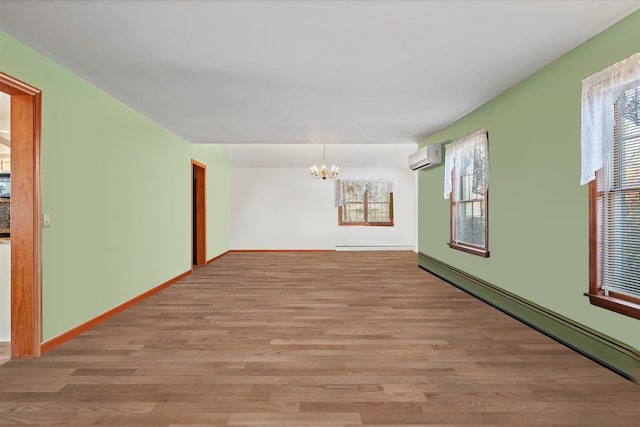 157 Pier Ave, Jamesport, NY 11901 - spare room featuring an AC wall unit, a chandelier, light wood-style flooring, and a baseboard heating unit