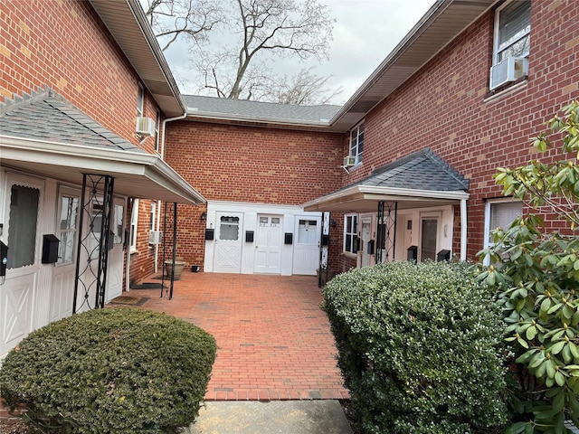 view of side of home with a shingled roof and brick siding