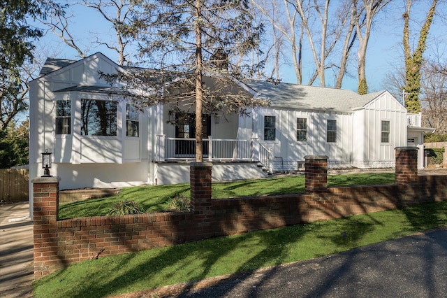 view of front of house featuring board and batten siding, a front yard, and covered porch