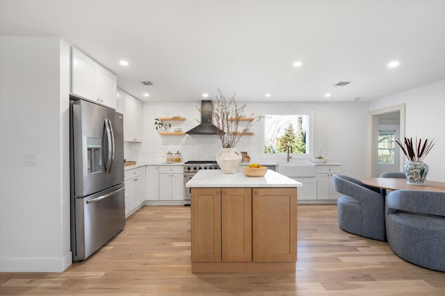 kitchen with a sink, stainless steel appliances, exhaust hood, and visible vents