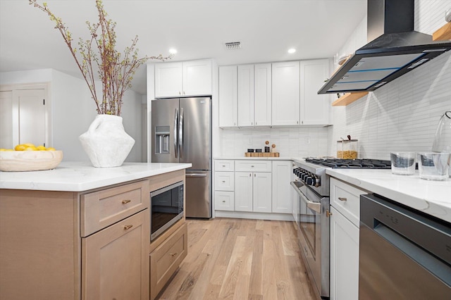 kitchen with tasteful backsplash, visible vents, appliances with stainless steel finishes, island exhaust hood, and light wood-style floors