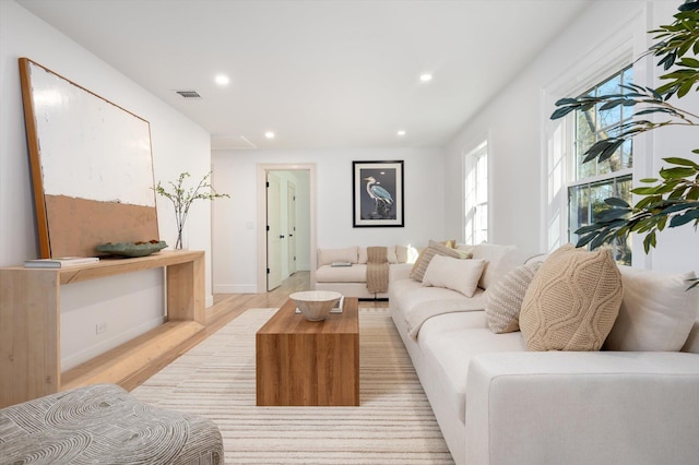 living area with light wood-style flooring, visible vents, baseboards, and recessed lighting