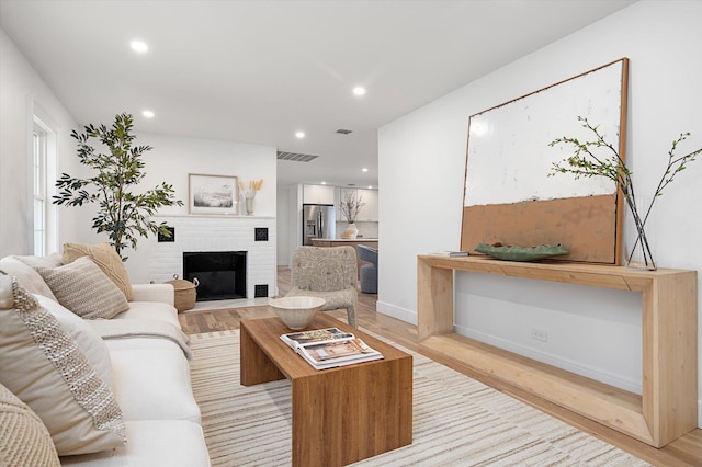 living room with light wood-style floors, recessed lighting, visible vents, and a fireplace