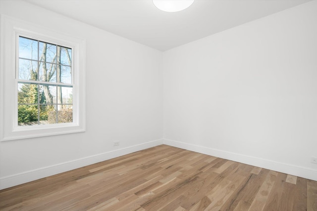 unfurnished room featuring light wood-style flooring, a wealth of natural light, and baseboards