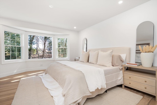 bedroom with baseboards, wood finished floors, and recessed lighting