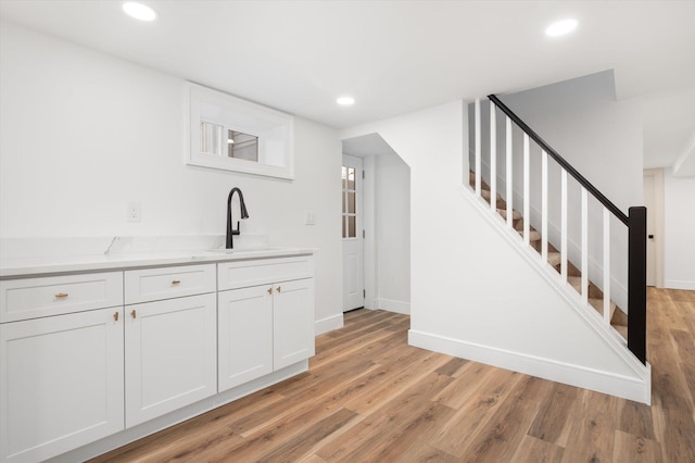 bar with stairway, light wood-type flooring, a sink, and recessed lighting