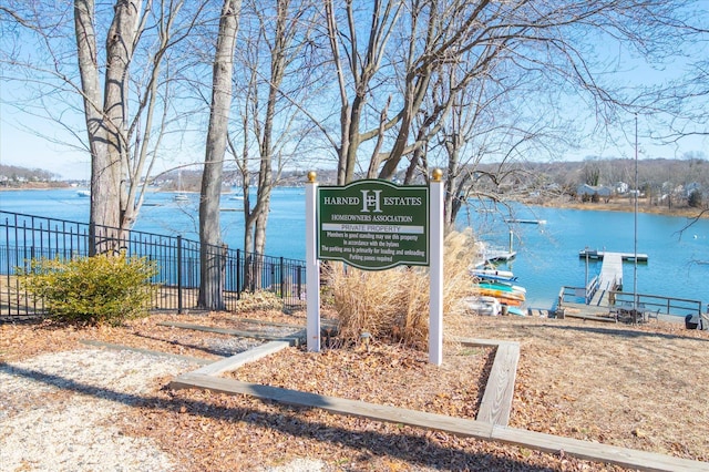 exterior space with a water view, fence, and a boat dock