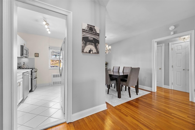 dining area featuring light wood-style floors, visible vents, baseboards, and an inviting chandelier