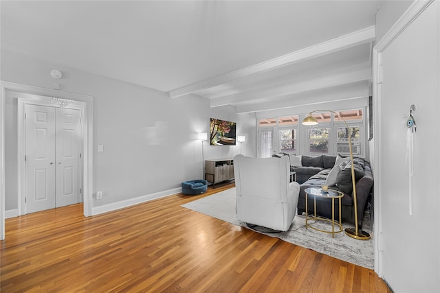 living room with beam ceiling, baseboards, and wood finished floors