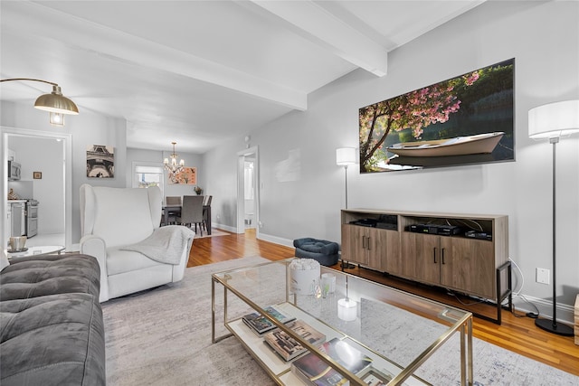 living room featuring a notable chandelier, beamed ceiling, wood finished floors, and baseboards