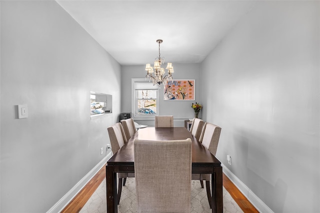 dining room with light wood-type flooring, baseboards, and a notable chandelier