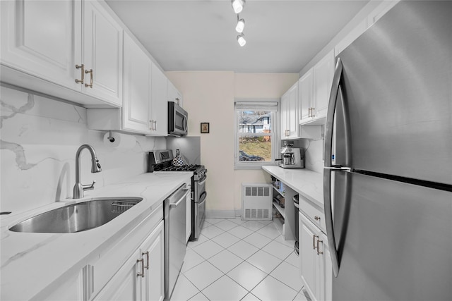 kitchen featuring appliances with stainless steel finishes, white cabinetry, a sink, and decorative backsplash