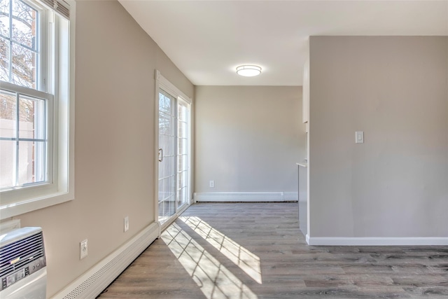 foyer entrance with a wealth of natural light, a baseboard radiator, baseboard heating, and wood finished floors