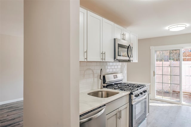 kitchen with light wood finished floors, appliances with stainless steel finishes, a sink, and decorative backsplash