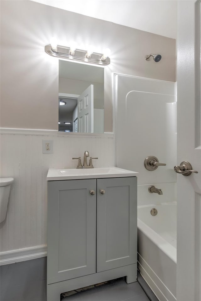 full bath with toilet, wainscoting, bathtub / shower combination, and vanity