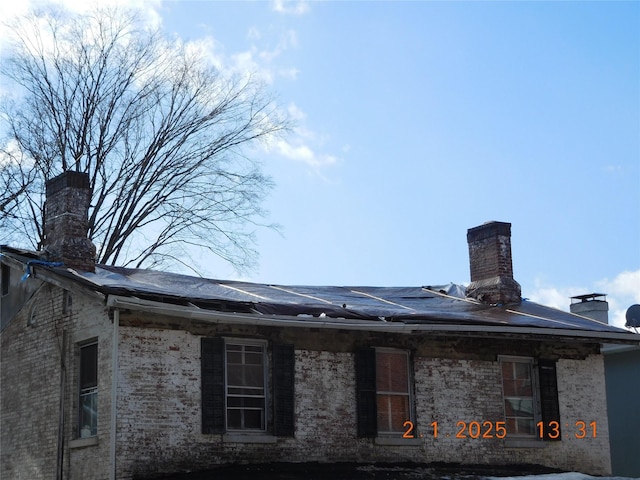 exterior space with roof mounted solar panels and a chimney