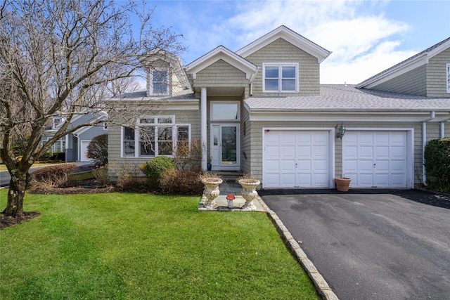 view of front of property featuring a front yard, roof with shingles, driveway, and an attached garage