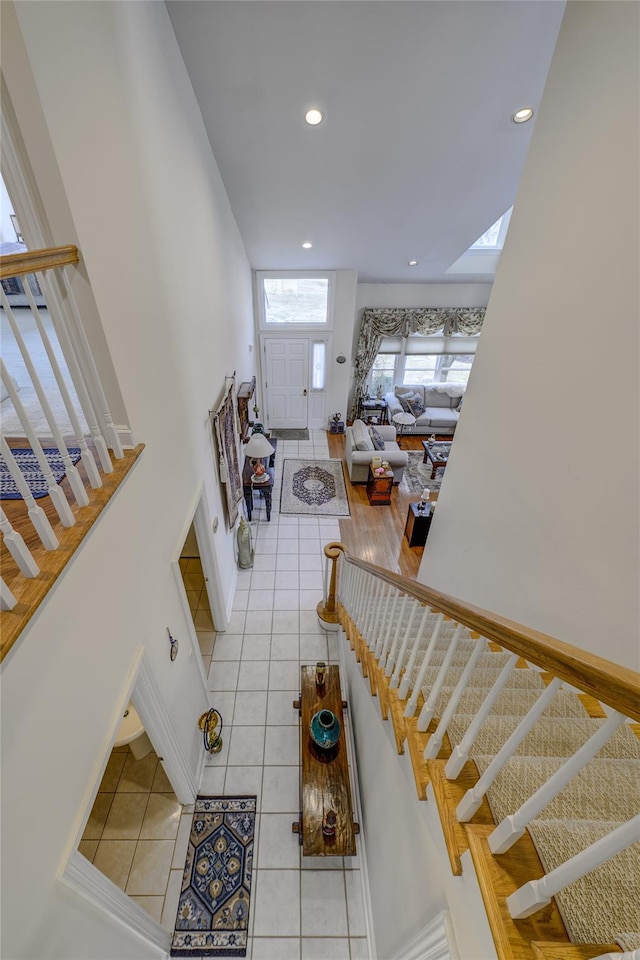 stairs with baseboards, a skylight, tile patterned flooring, and recessed lighting