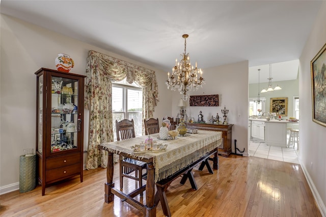 dining space with a notable chandelier, light wood-style flooring, and baseboards