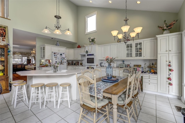 dining space with light tile patterned floors, high vaulted ceiling, and a notable chandelier