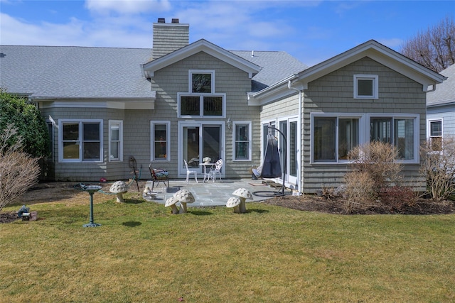 back of house featuring a yard, roof with shingles, a patio, and a chimney