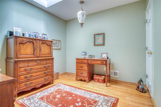 office with a skylight, baseboards, and light wood-style floors