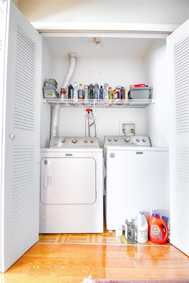 clothes washing area featuring laundry area, washing machine and clothes dryer, and light wood-style flooring