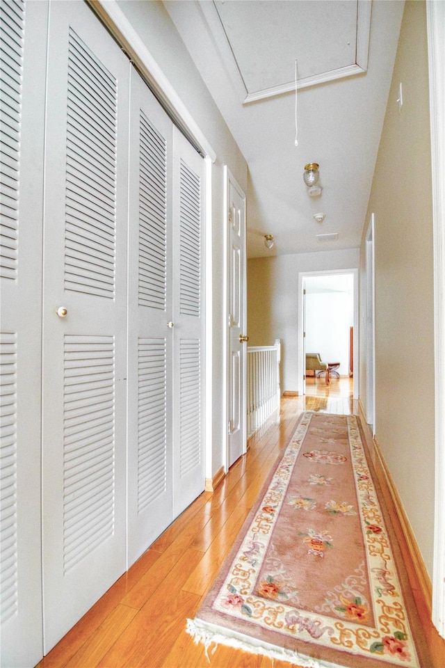 hallway featuring attic access and light wood-style flooring