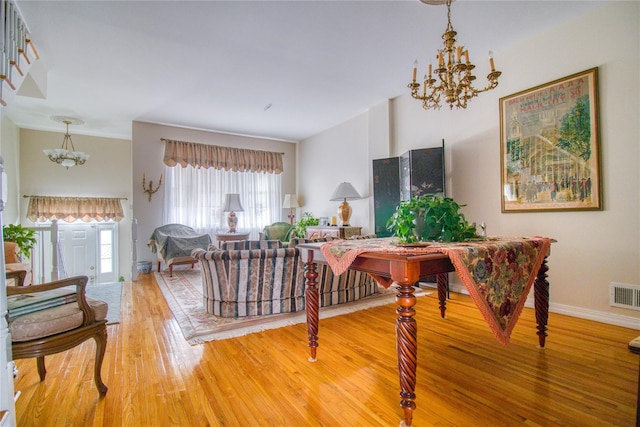 interior space with baseboards, visible vents, a notable chandelier, and wood finished floors