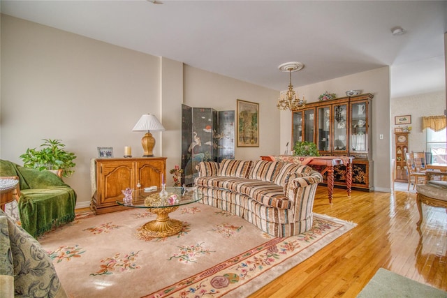 living room featuring a chandelier, baseboards, and light wood finished floors