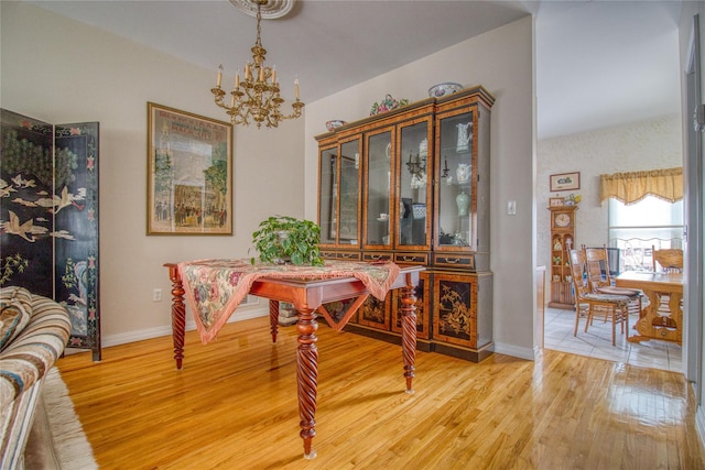 dining area with baseboards, a notable chandelier, and light wood finished floors