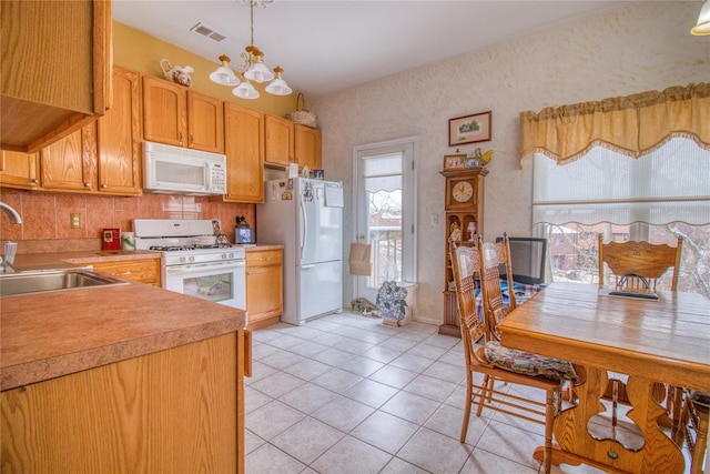 kitchen featuring light countertops, visible vents, a sink, a chandelier, and white appliances