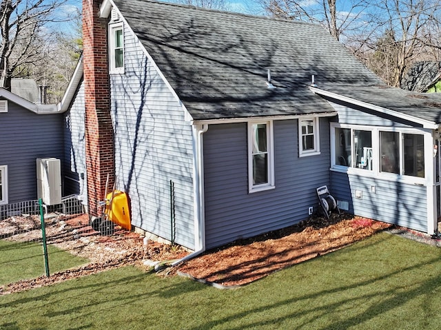 view of property exterior with roof with shingles, a yard, a chimney, and a sunroom