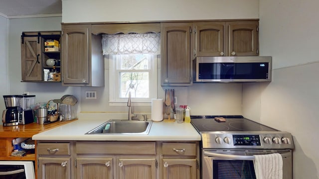 kitchen with crown molding, appliances with stainless steel finishes, light countertops, and a sink