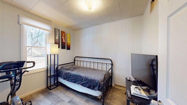 bedroom with multiple windows, baseboards, and wood finished floors