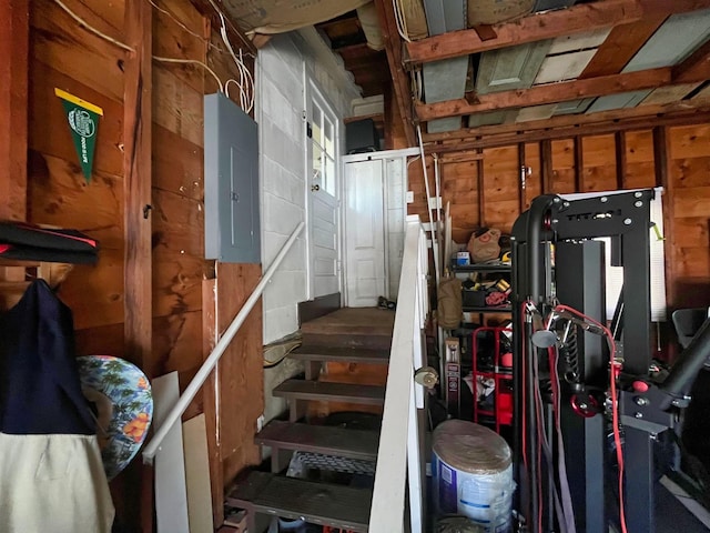 stairs featuring concrete block wall and electric panel