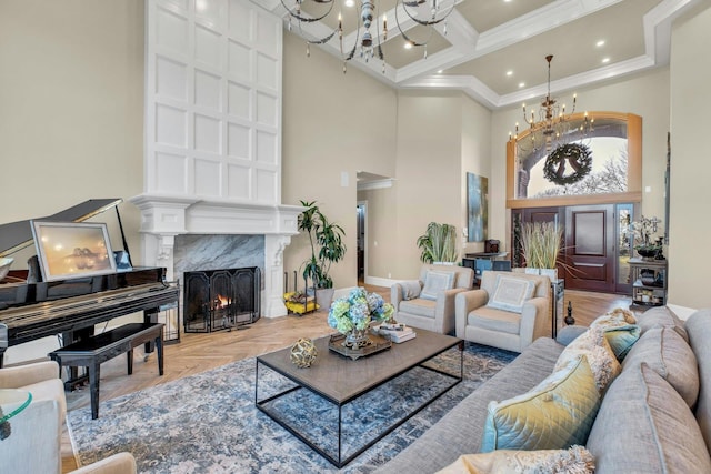 living room with a notable chandelier, a high ceiling, a premium fireplace, ornamental molding, and coffered ceiling