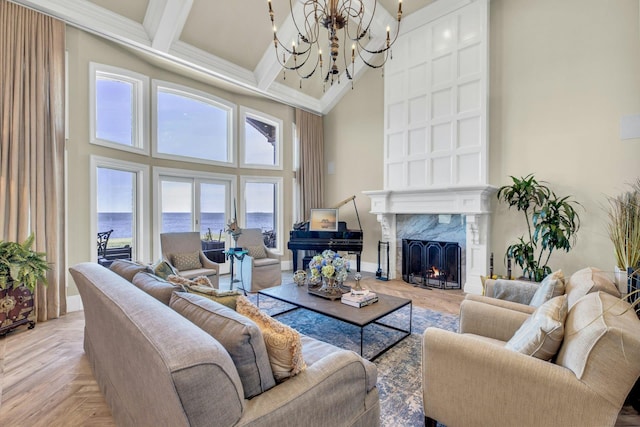 living room featuring a chandelier, a towering ceiling, a high end fireplace, ornamental molding, and beamed ceiling