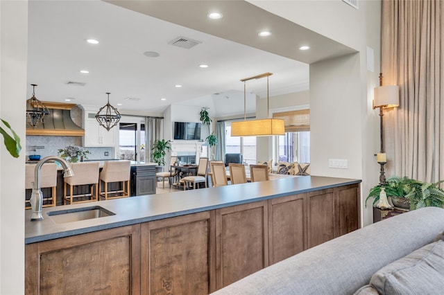 kitchen featuring recessed lighting, a sink, visible vents, vaulted ceiling, and hanging light fixtures